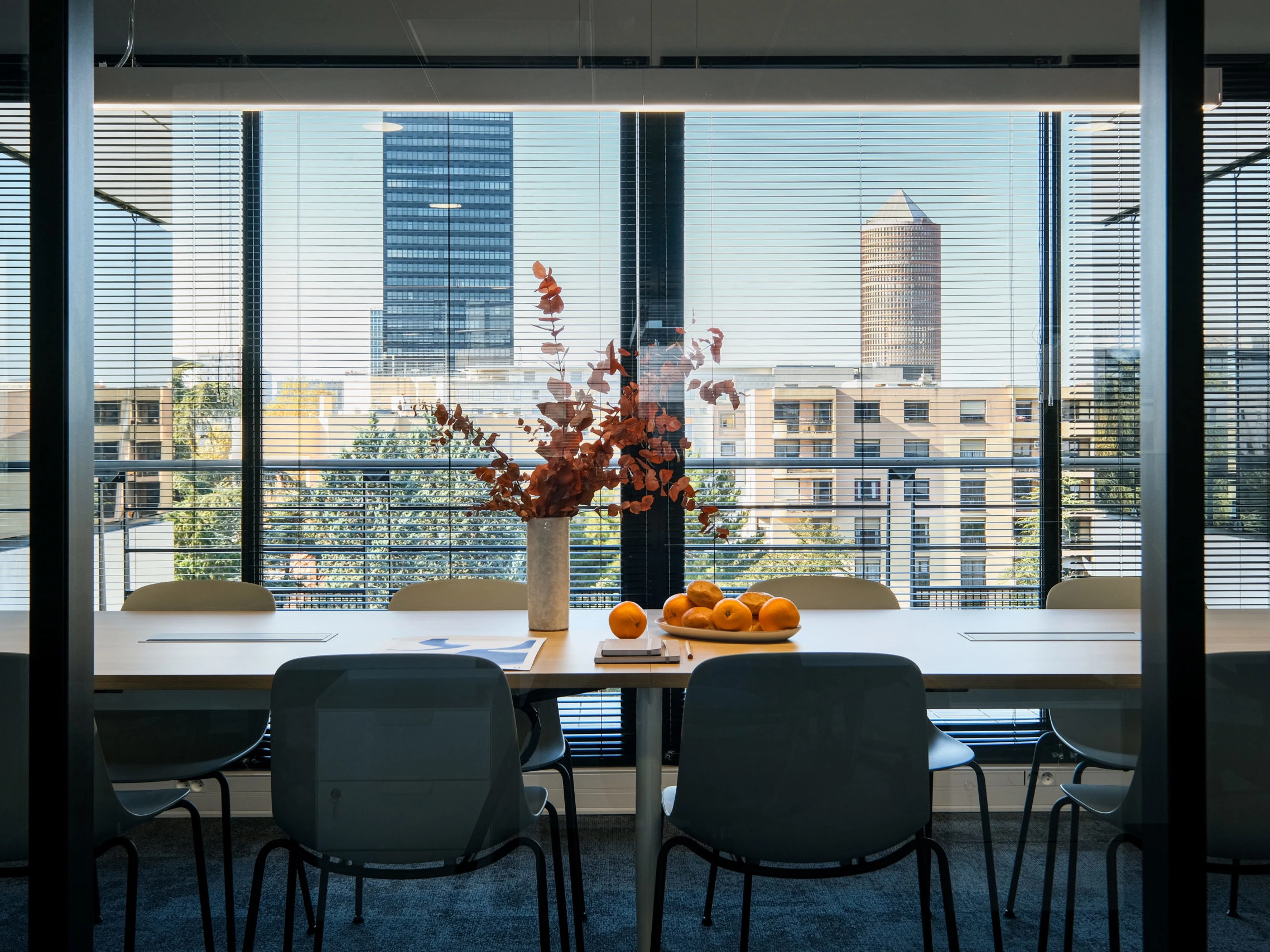 Salle de réunion avec table ovale et chaises grises face à la skyline de la Part-Dieu à Lyon, ESQUI STUDIO