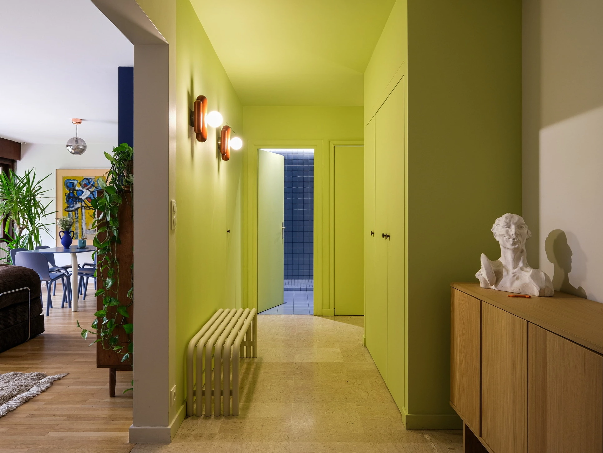 Couloir vert chartreuse ouvert sur un séjour coloré, enfilade chêne et buste en plâtre, ESQUI STUDIO Lyon