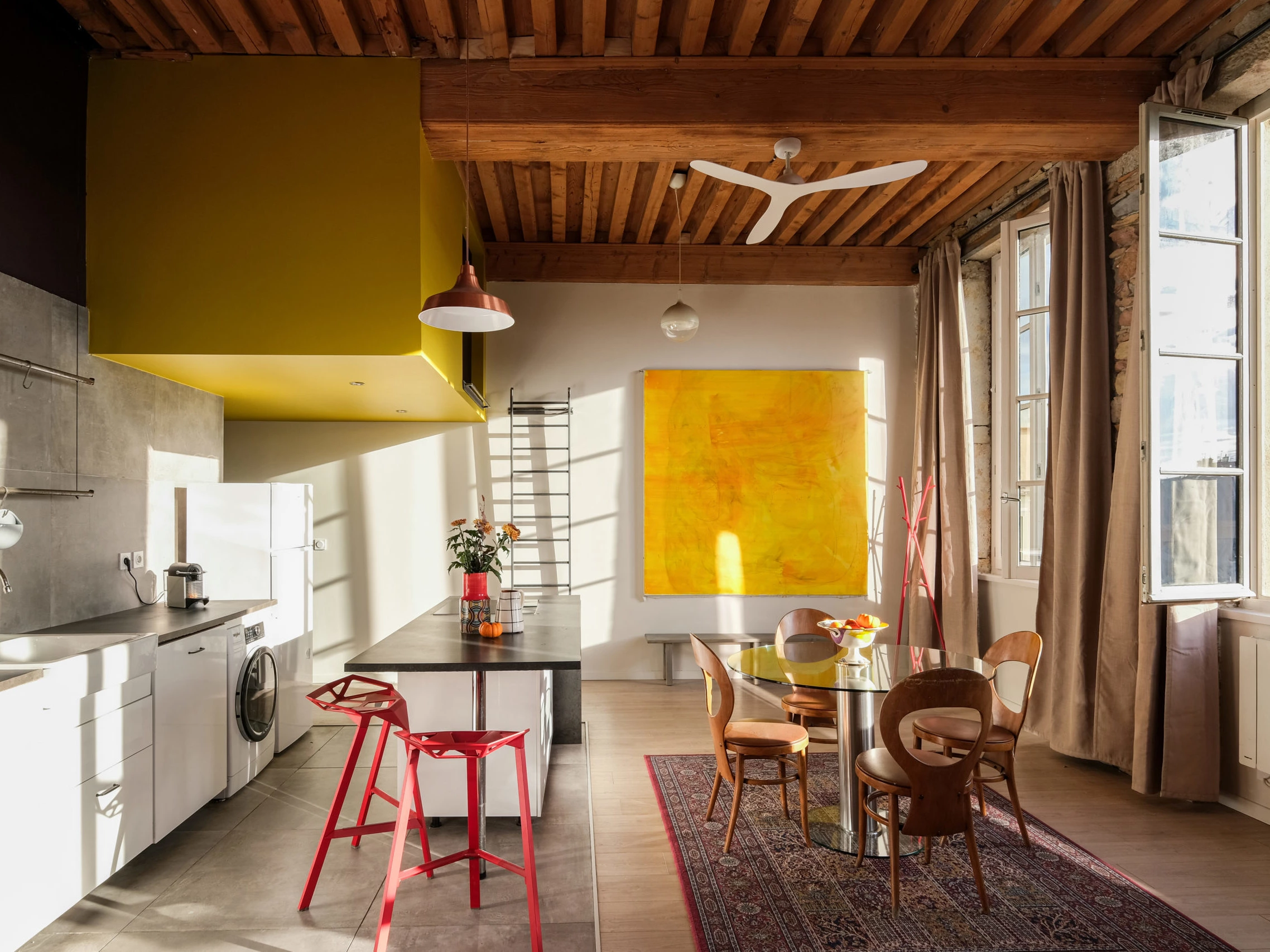 Cuisine de loft en longueur avec volume jaune, tabourets rouges et grande œuvre jaune, vue Lyon, ESQUI STUDIO